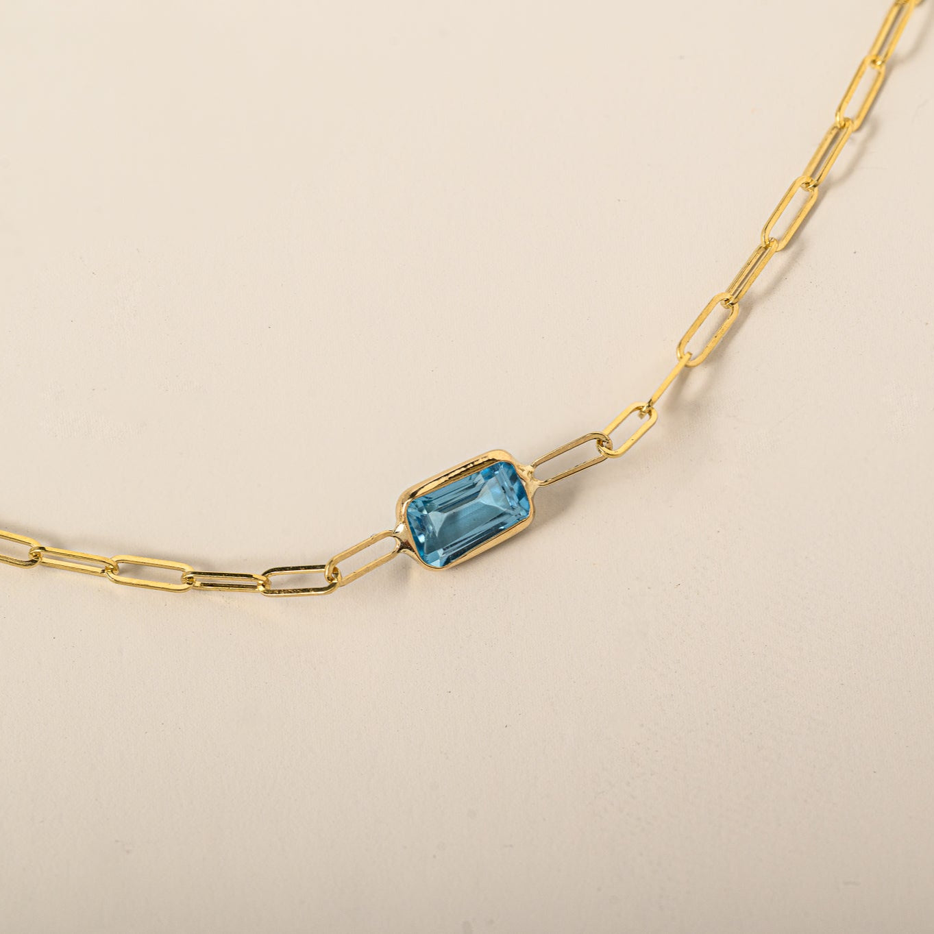 14k yellow gold emerald cut east west bezel set blue topaz paperclip chain bracelet