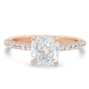 14k rose or peach gold semi custom engagement ring with a cushion diamond center stone and diamonds on the band, rail and shank of the ring