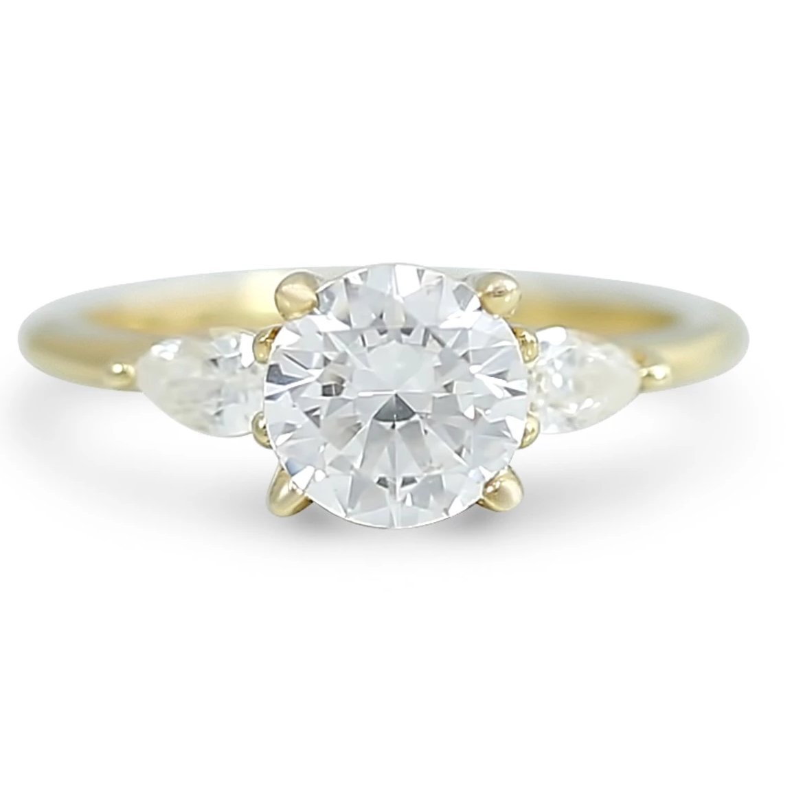 three stone ready to buy diamond engagement ring with pear shaped side stones prong set and available in 14k yellow, white, rose, or peach gold and platinum