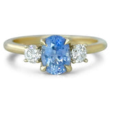 14k yellow gold three stone light blue oval sapphire engagement ring with petal prongs and two round brilliant cut diamondfs on each side.