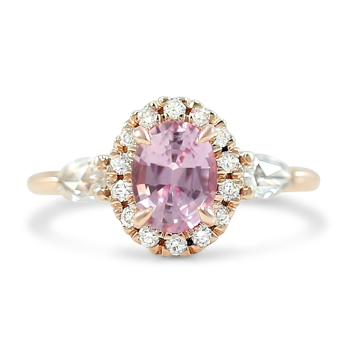 1.31ct pink oval sapphire set in 14k rose gold with a diamond halo and pear shaped diamond side stones